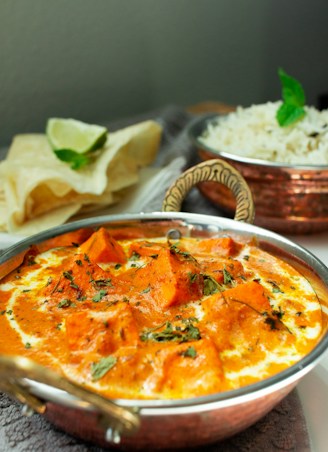 a metal bowl filled with food next to a bowl of rice