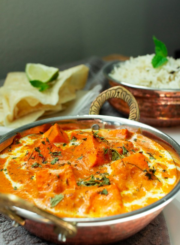 a metal bowl filled with food next to a bowl of rice